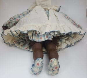 Vintage doll in plaid dress lying down.