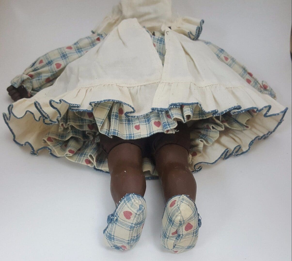 Vintage doll in plaid dress lying down.