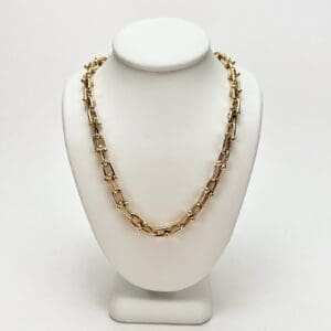 Gold chain necklace on display stand.