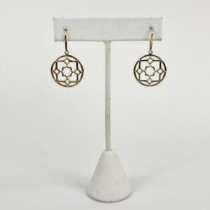 Gold geometric earrings on white stand.
