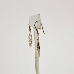 Gold filigree earrings on display stand.
