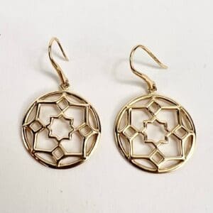 Gold geometric pattern earrings on display.