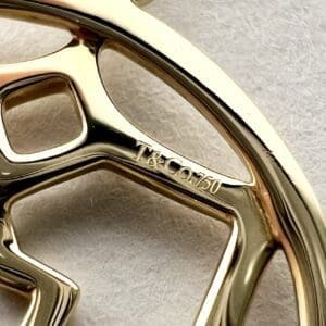 Gold jewelry piece with "T&Co.750" engraving.