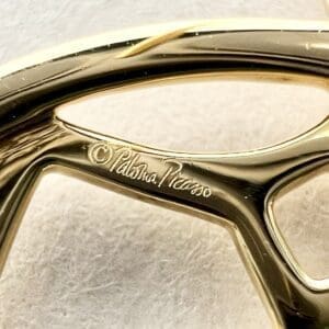 Gold sculpture with engraved signature detail.