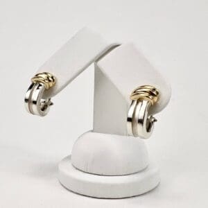 Silver and gold hoop earrings on stand.