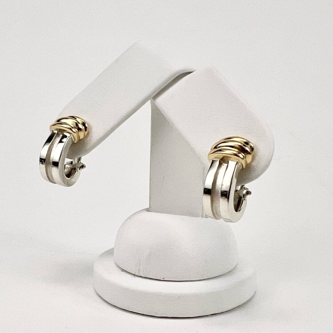 Silver and gold hoop earrings on stand.