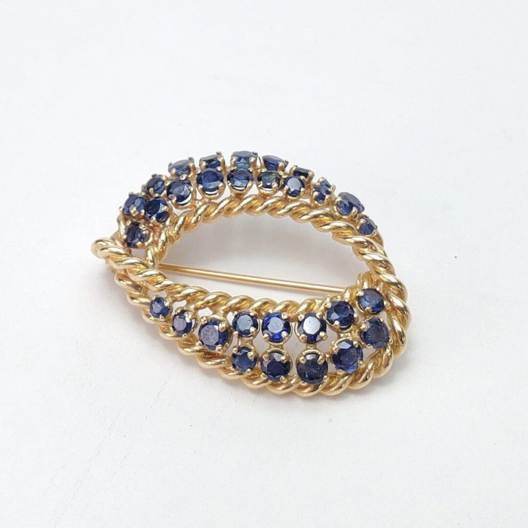 Gold brooch with blue gemstones on white.