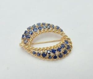 Gold brooch with blue gemstones on display.