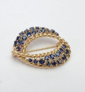 Gold brooch with blue gemstones on white.