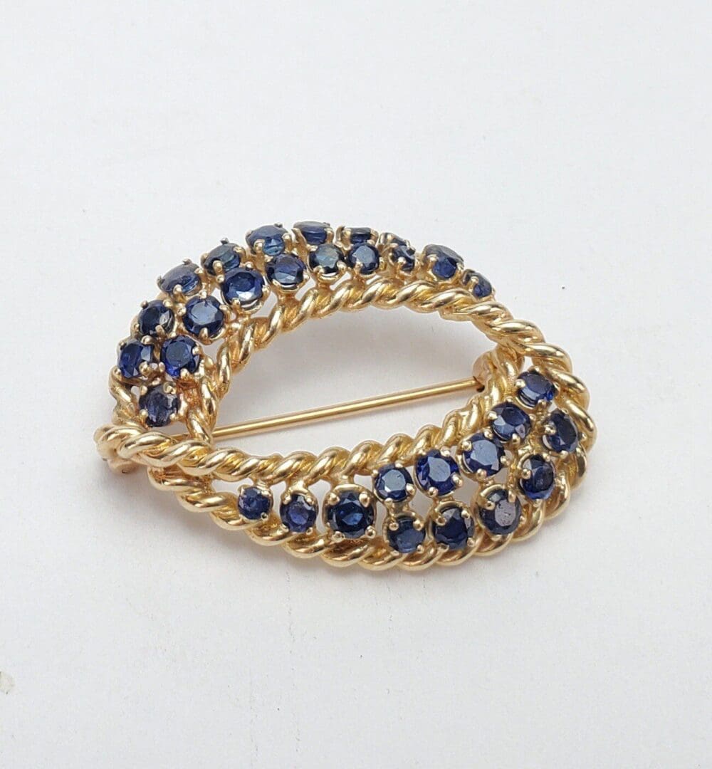 Gold brooch with blue gemstones on white.