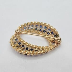 Gold brooch with blue gemstone accents.