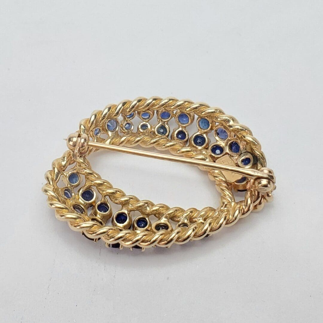 Gold brooch with blue gemstone accents.