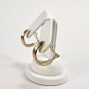 Gold hoop earrings on white stand.
