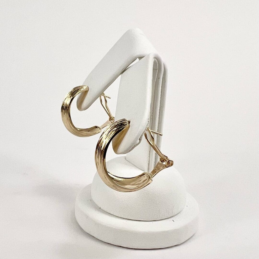 Gold hoop earrings on white stand.