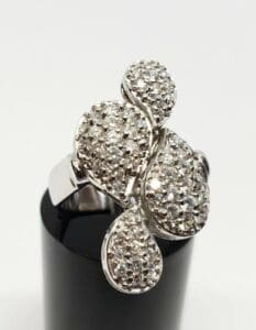 Diamond-studded silver ring on black stand.