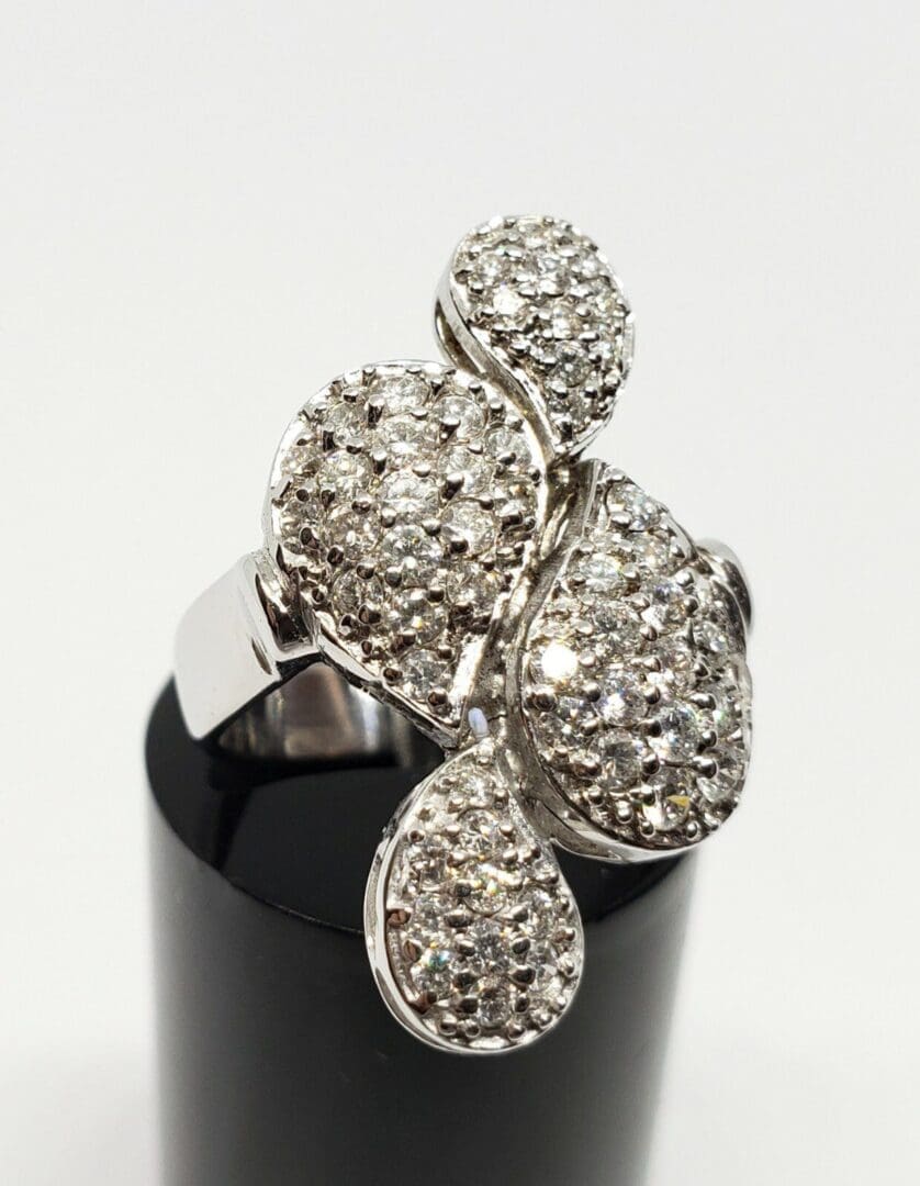 Diamond-studded silver ring on black stand.