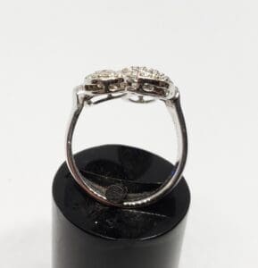 Silver ring with diamond accents on stand.