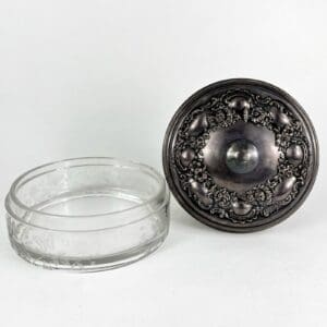 Glass container with ornate metal lid.