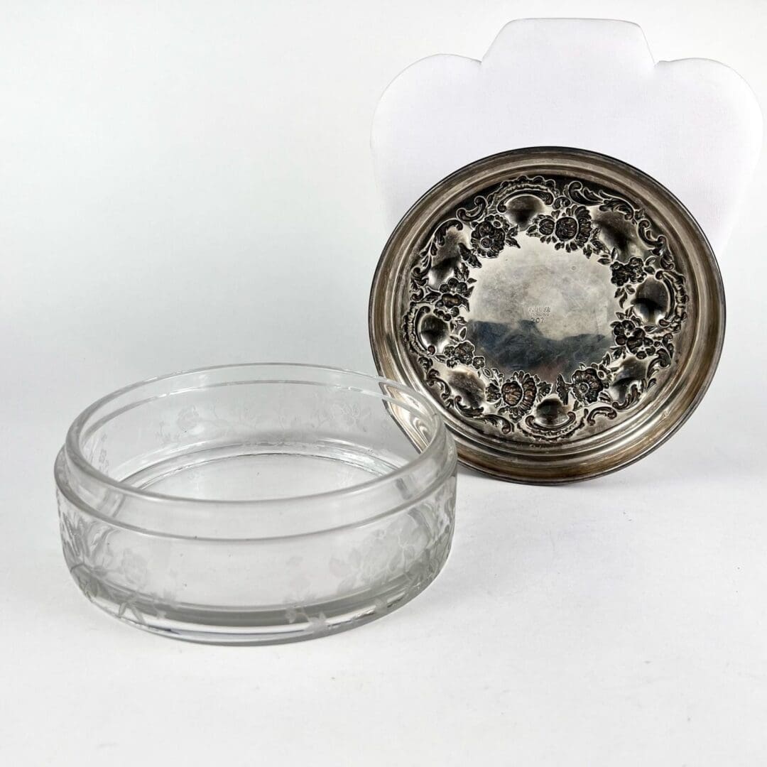 Glass bowl with ornate silver lid.