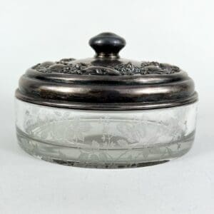 Glass jar with ornate metallic lid.