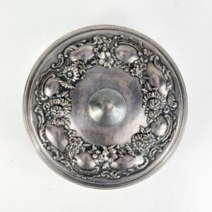 Ornate silver lid with floral decoration.