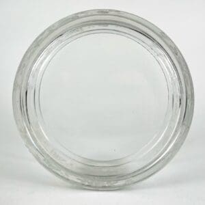 Clear glass jar lid on white background.