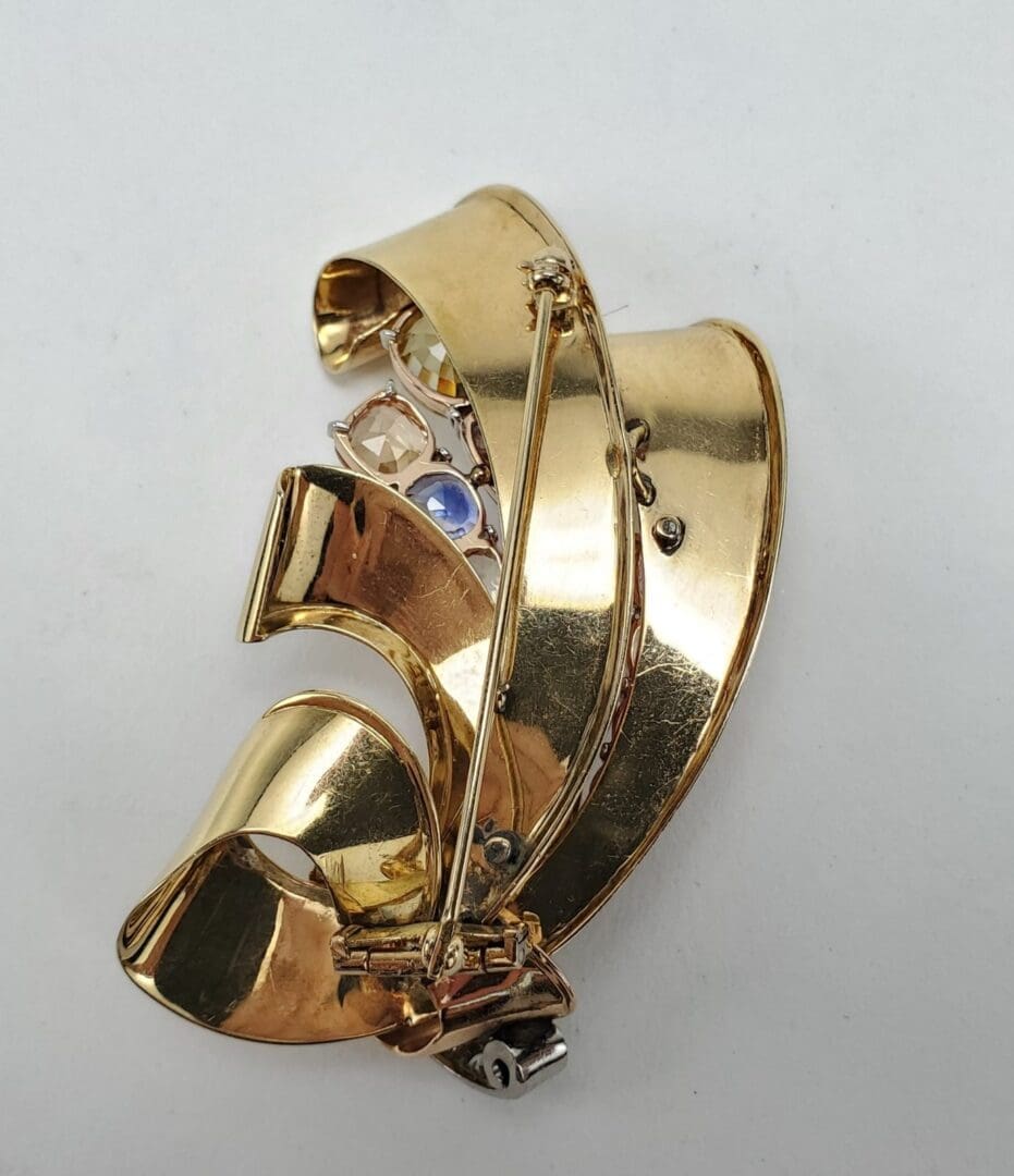 Gold brooch with intricate, curved design.