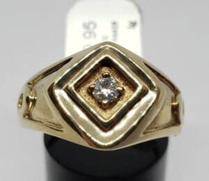 Gold ring with diamond on display stand.
