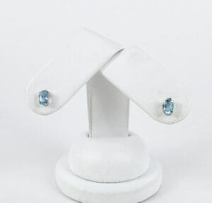 Blue gemstone earrings on white display stand.