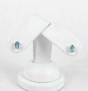 Blue gemstone earrings on white display stand.