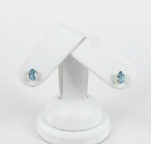 Blue gemstone earrings on white display stand.