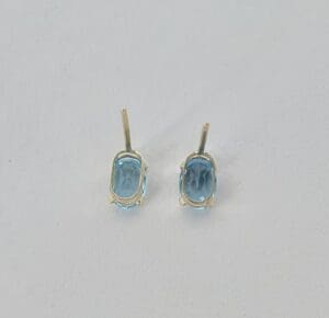 Gold earrings with blue oval gemstones.