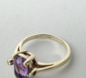 Gold ring with purple gemstone on display.