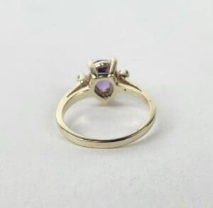 Gold ring with purple gemstone on display.