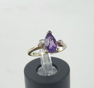 Gold ring with purple teardrop gemstone.