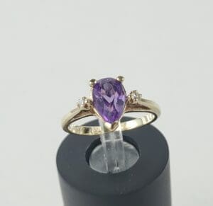 Gold ring with purple gemstone and diamonds.
