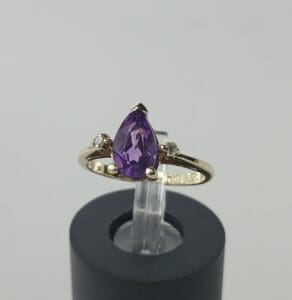 Gold ring with purple gemstone centerpiece.