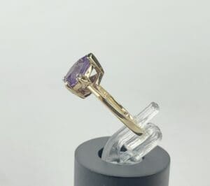 Gold ring with purple gemstone displayed.