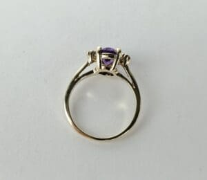 Gold ring with purple gemstone on display.