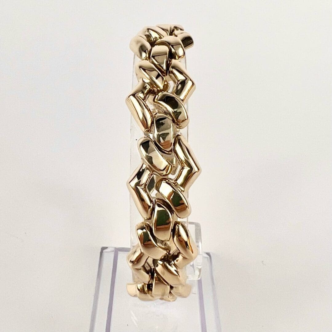 Gold chain bracelet on clear display stand.