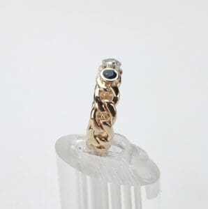 Gold chain ring with gemstones on display.