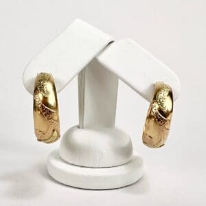 Gold hoop earrings on display stand.