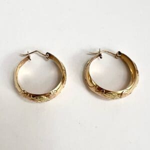 Gold hoop earrings with engraved floral design.