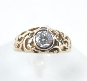 Gold ring with ornate design and diamond.