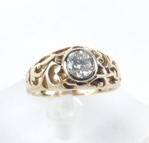 Gold ring with ornate design and diamond.