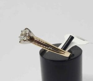 Gold ring with a diamond on stand.