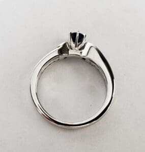 Silver engagement ring with dark gemstone setting.