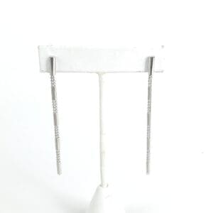 Silver drop earrings on a white stand.