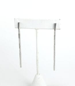 Silver dangle earrings on display stand.