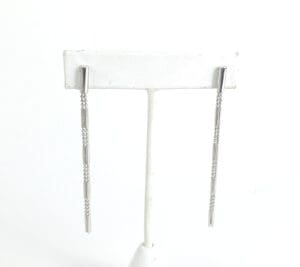 Silver drop earrings on display stand.